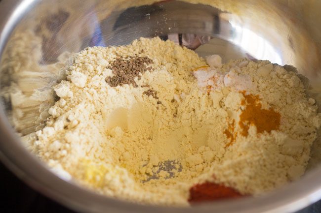 carom seeds and asafoetida added to the mixing bowl for sev recipe. 