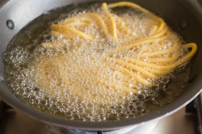 frying besan sev in hot oil.