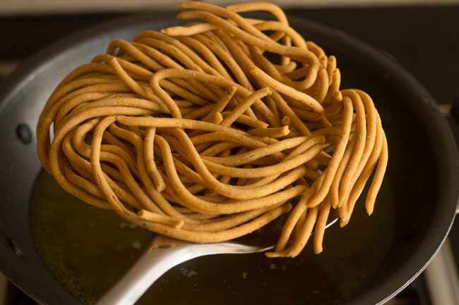 removing fried besan sev from hot oil.