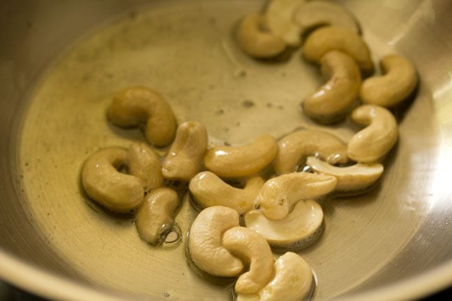 cashews added to hot ghee or oil in pan. 