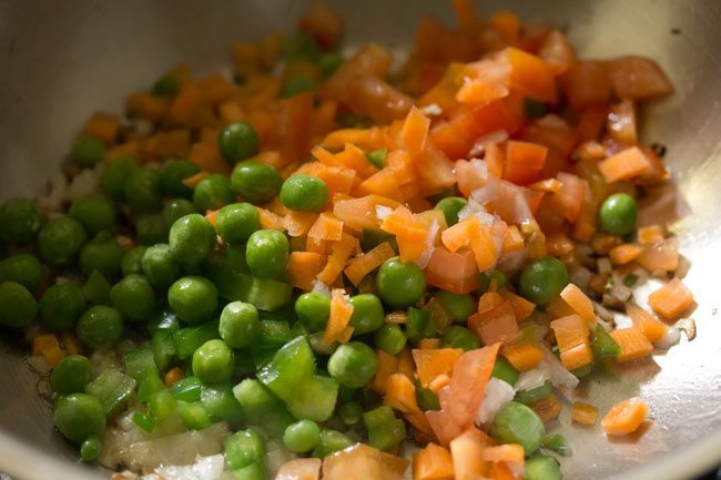 finely chopped capsicum, finely chopped carrot, finely chopped tomatoes and green peas added to the pan. 