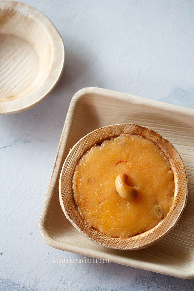 kesari bath garnished with a fried cashew and served in a bamboo bowl with text layover. 