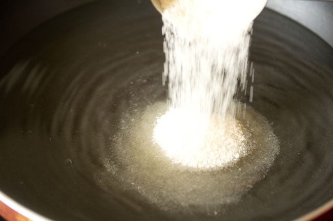 adding sugar to the water in the pan. 