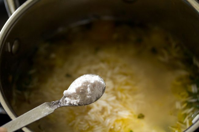 adding salt to the rice mixture in the pan. 