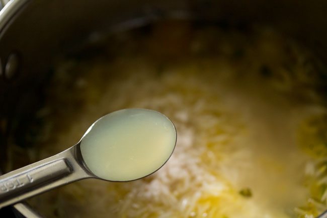 adding lemon juice to the rice mixture in the pan.  