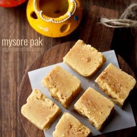 cubes of mysore pak on a wooden serving tray on a table.