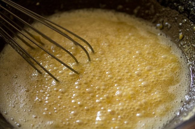 whisking besan into syrup for making mysore pak recipe