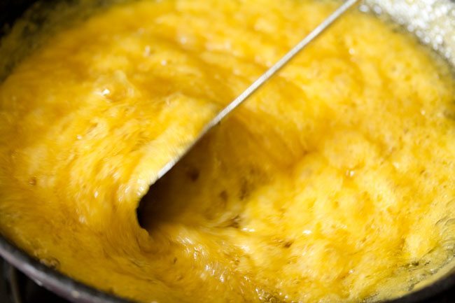 stirring the mysore pak batter to incorporate ghee - mixture is thick, slighly separated and a honeycomb yellow color