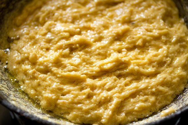 preparing mysore pak recipe - when it isn't being stirred, the dough looks shiny, light golden yellow with a small slick of ghee at the sides of the pan.