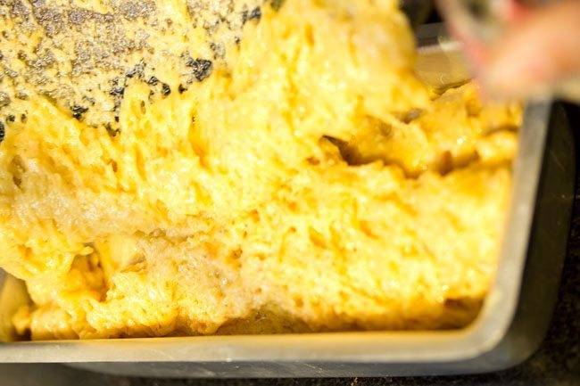 completed mysore pak batter being poured into prepared loaf pan