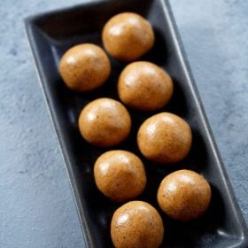 sattu ladoo served on a black rectangular platter with text layover.