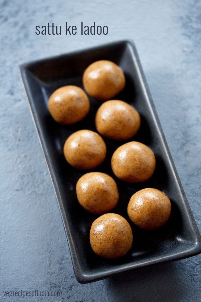 sattu ladoo served on a black rectangular platter with text layover.