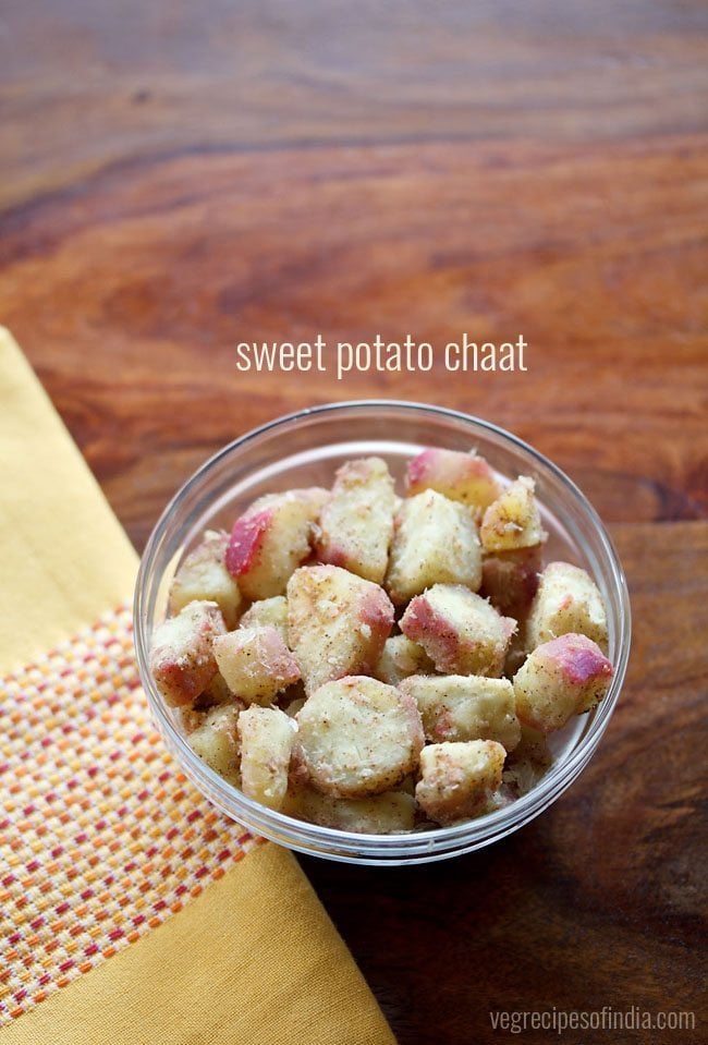 sweet potato chaat snack in a glass bowl with yellow embroidered napkin on left side with text layovers.