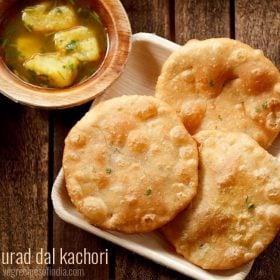 urad dal kachori served on a white platter with a bowl of aloo rasedar on the left side and text layovers.