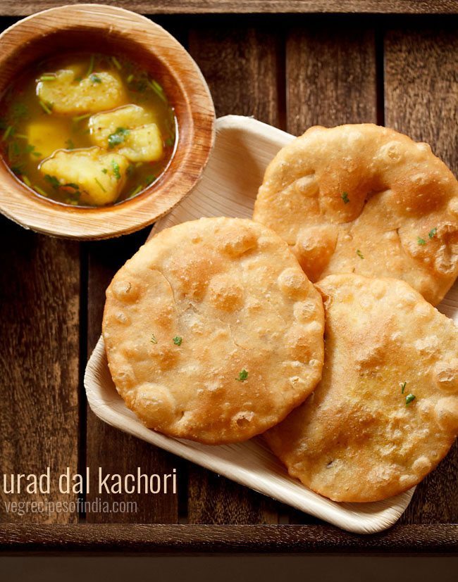 urad dal kachori served on a white platter with a bowl of aloo rasedar on the left side and text layovers.