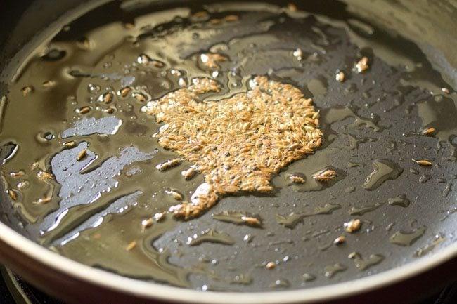 cumin seeds sizzling in hot ghee in pan. 