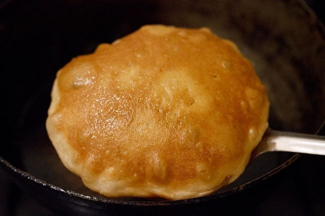 removing fried kachori with a slotted spoon. 