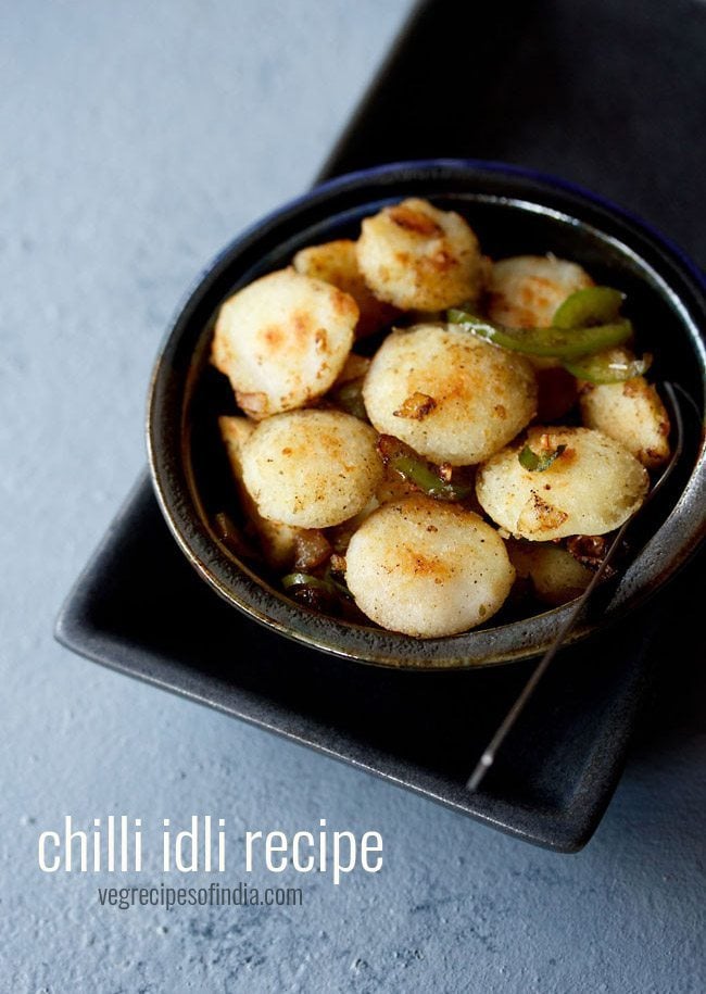 chilli idli served in a ceramic bowl with a spoon in it and text layovers.