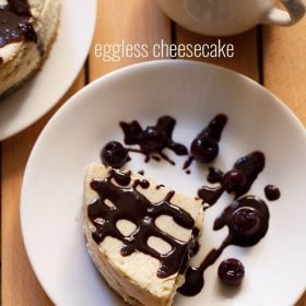 new york style cheesecake wedge drizzled with chocolate sauce and topped with black berries on white plate.