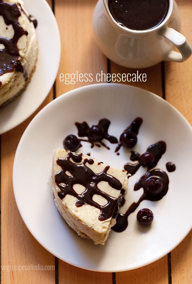 new york style cheesecake wedge drizzled with chocolate sauce and topped with black berries on white plate.