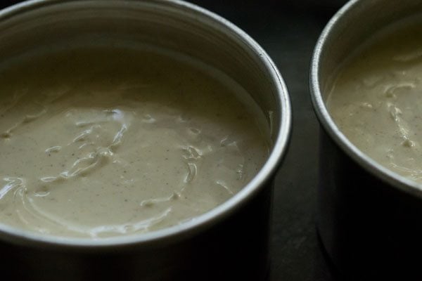 two cheesecake springform pans on a cooking sheet in the oven