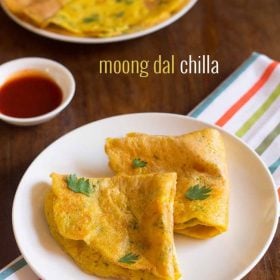 moong dal chilla folded and garnished with coriander leaves, served on white plate with a small bowl of tomato ketchup kept on the top left side and text layover.