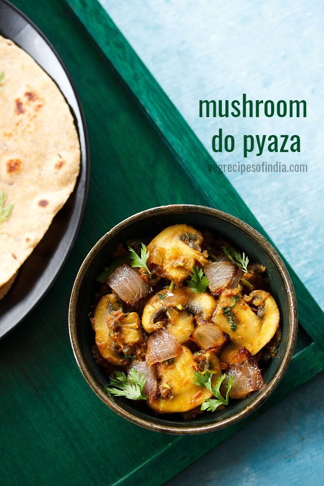 mushroom do pyaza garnished with cilantro sprigs in a dark olive green ceramic bowl on a dark green board with a side of roti with text layovers.