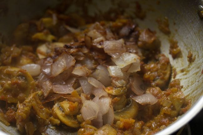 sautéed onion cubes added to cooked mushrooms to make mushroom do pyaza