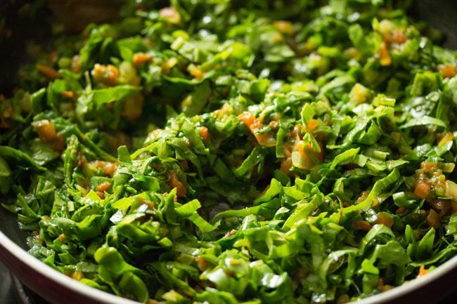 mixing spinach with tomato masala