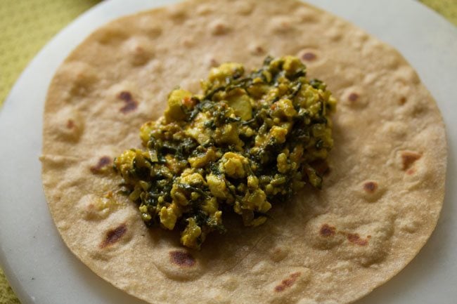 adding the spinach stuffing onto roti