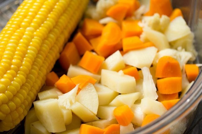 steamed mixed chopped vegetables and corn cob. 