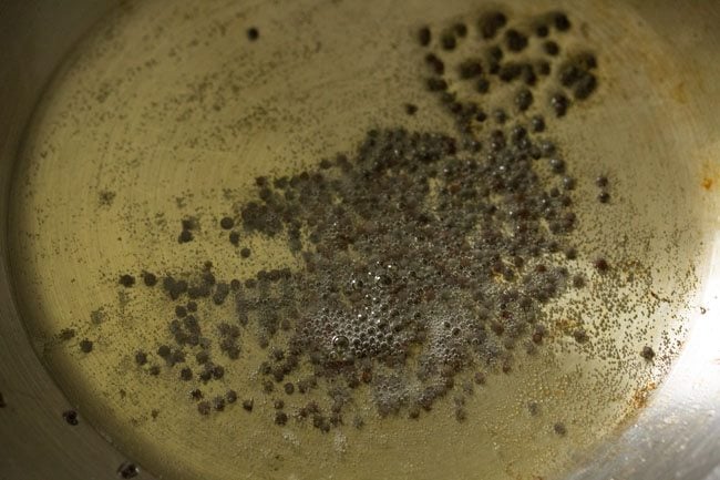 mustard seeds added to hot peanut oil in pan. 