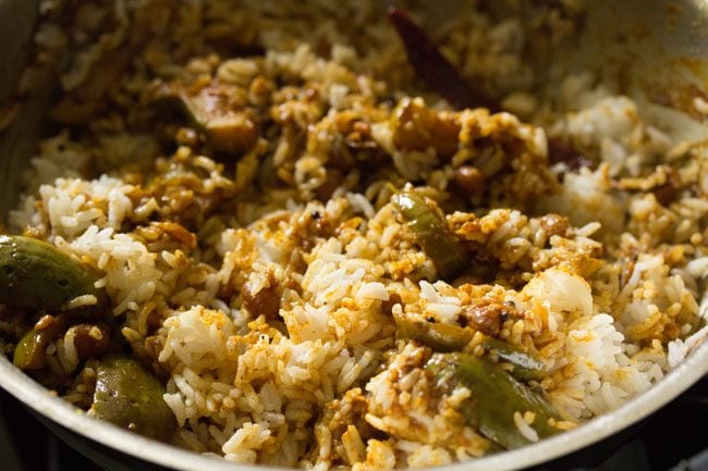 cooked rice mixed with the brinjal masala in the pan. 