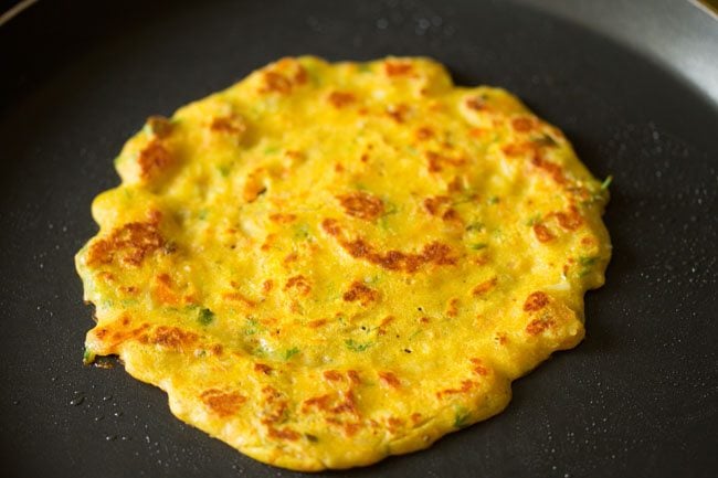 chilla with golden spots on frying pan