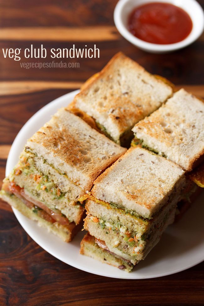 club sandwiches squares with layers seen on a white plate with tomato ketchup