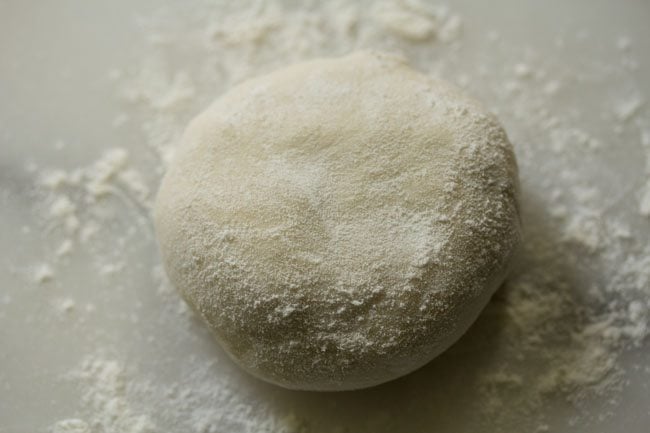 rolling and flattening a dough part, sprinkling flour on it