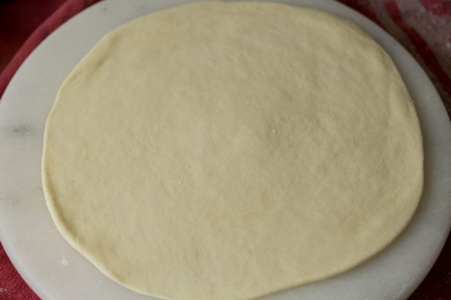 rolling dough into a round, thin pizza base
