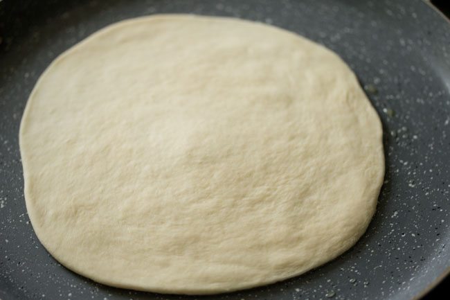 prepared pizza base on the hot tawa