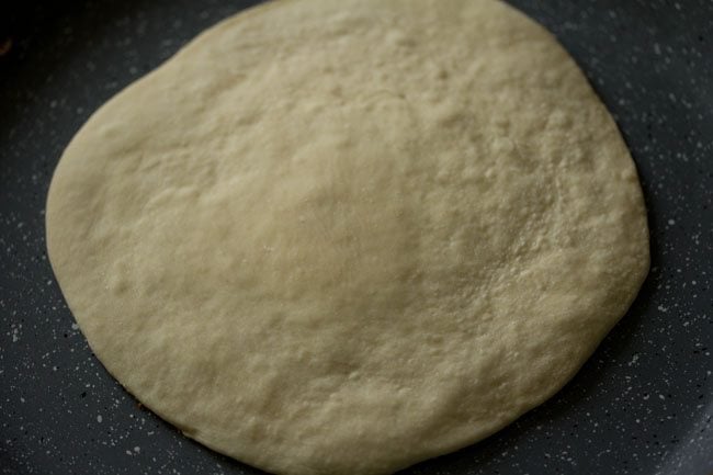 cooking the prepared pizza base on tawa