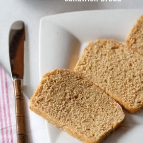 sandwich bread sliced and served on a white plate with a butter knife kept on the left side.