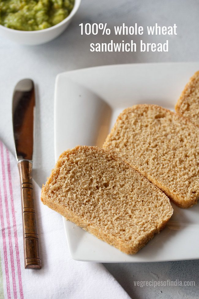 sandwich bread sliced and served on a white plate with a butter knife kept on the left side.