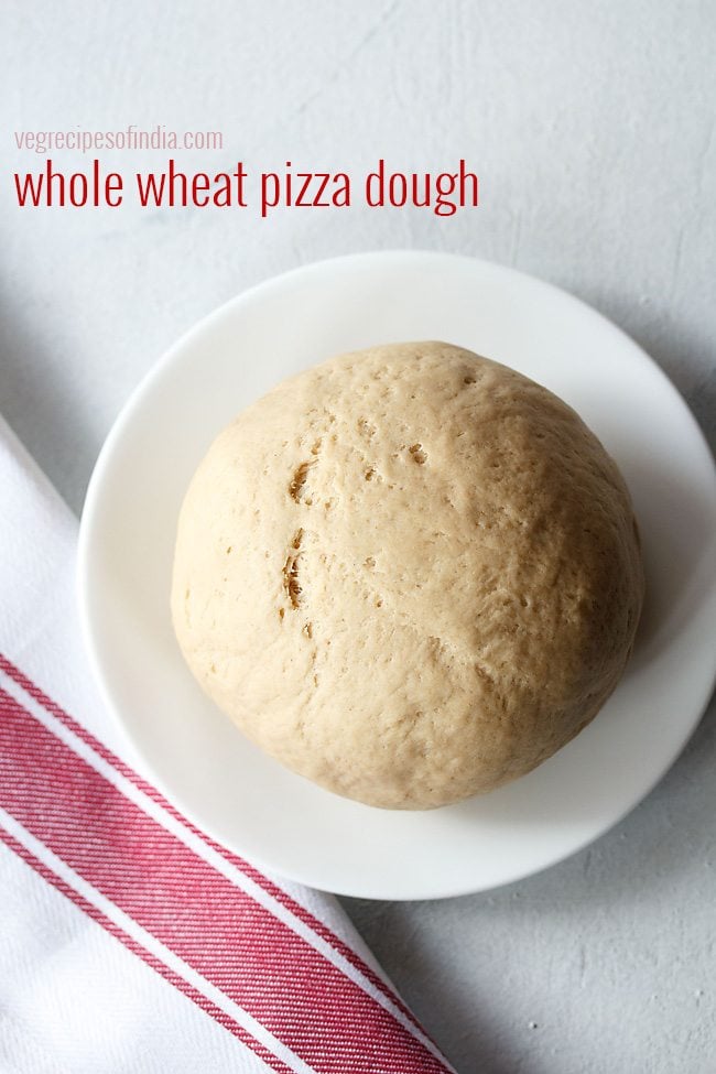 whole wheat pizza dough on a white plate with a red and white striped kitchen towel.