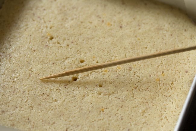 checking doneness of rava cake with a tooth pick