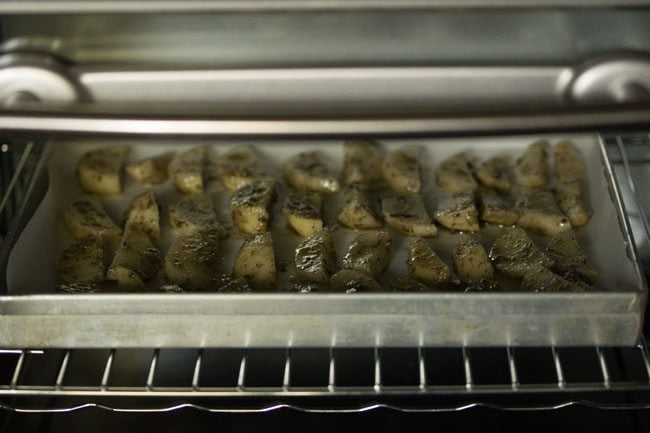  potato wedges in a baking tray in the oven