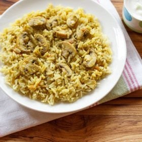 dindigul biryani served on a white plate with a small bowl of raita kept on the right side.