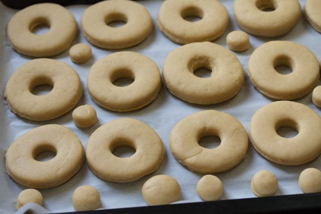 donuts placed on parchment paper on baking tray