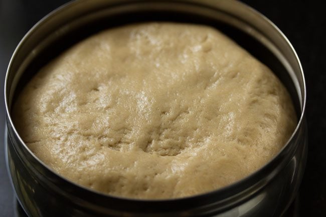 pizza dough placed in a round steel container