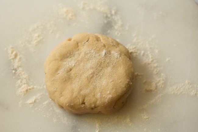 portion of dough flattened on a floored marble board