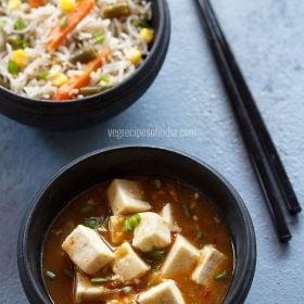 schezwan paneer served in a back bowl with a side of fried rice