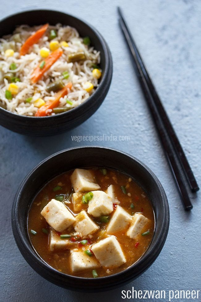 schezwan paneer served in a back bowl with a side of fried rice and text layover.